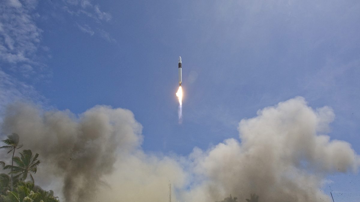 Falcon 1 rising on a column of smoke above palm trees on Omelek Island