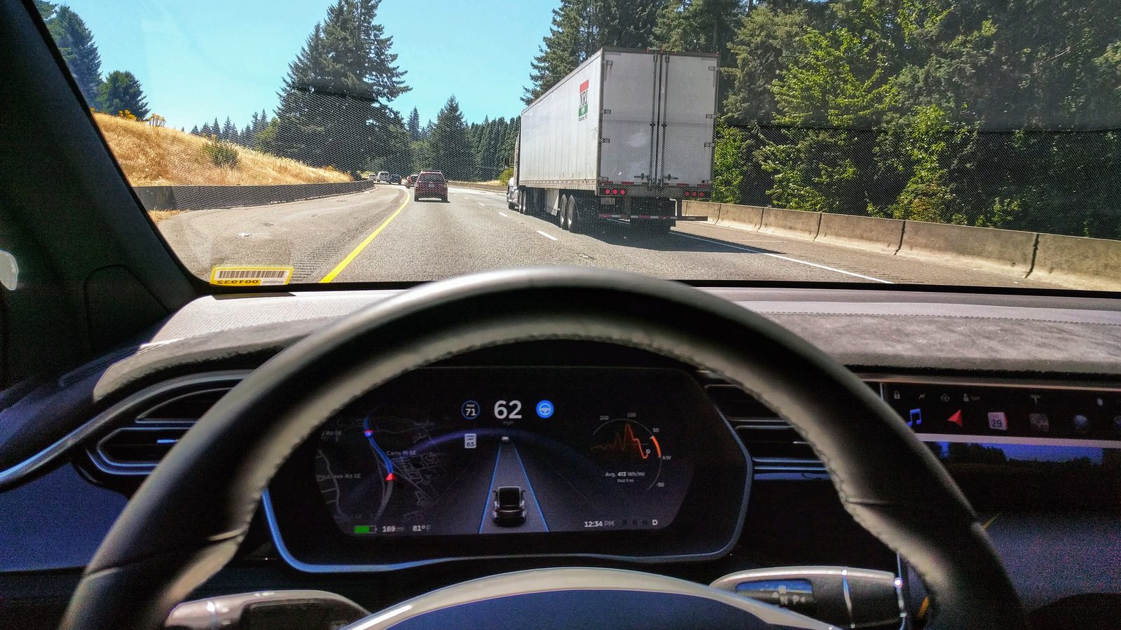 Tesla Model X instrument cluster showing Autopilot steering in highway traffic behind a truck