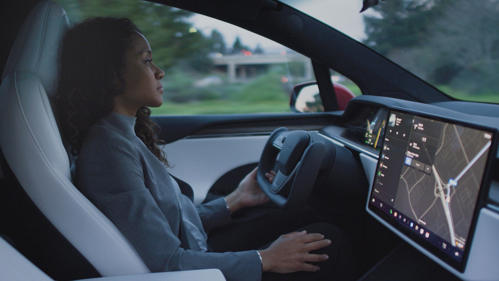 Driver supervising Full Self-Driving in a Tesla with a yoke and landscape screen