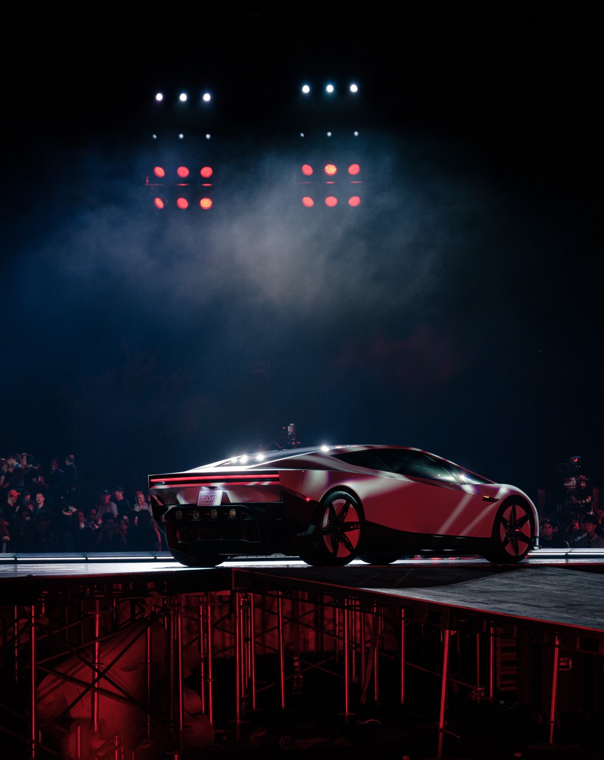 The white 2026 Tesla Roadster under red stage lights in front of the crowd at the reveal