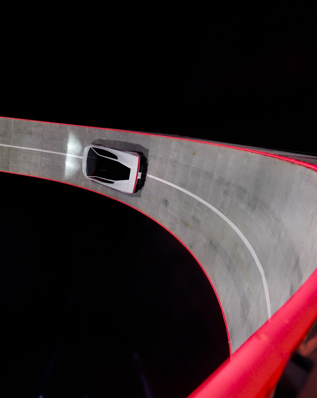 The 2026 Tesla Roadster driving up the steep wall of a giant curved ramp