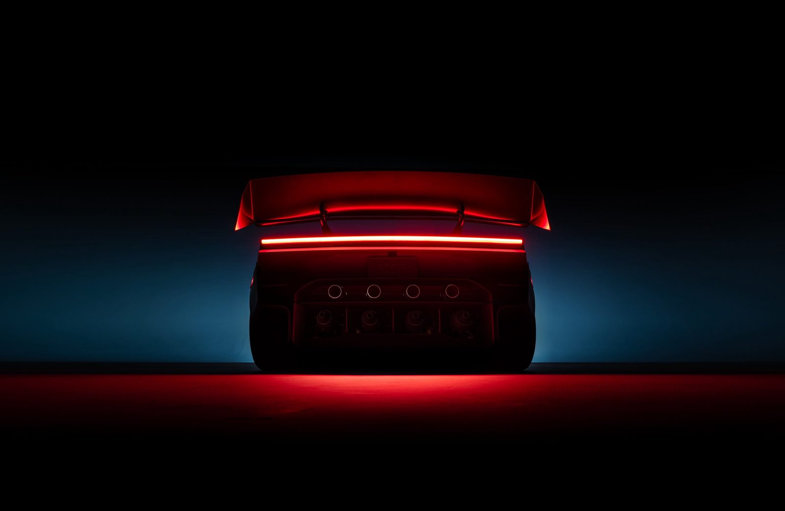 Rear of the 2026 Tesla Roadster lit red, showing its full-width taillight and a row of round thruster ports