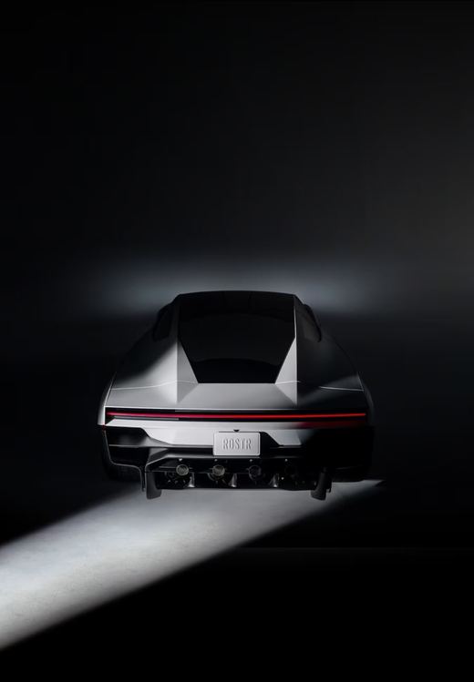 Rear view of the 2026 Tesla Roadster in a dark studio with a beam of light across the floor