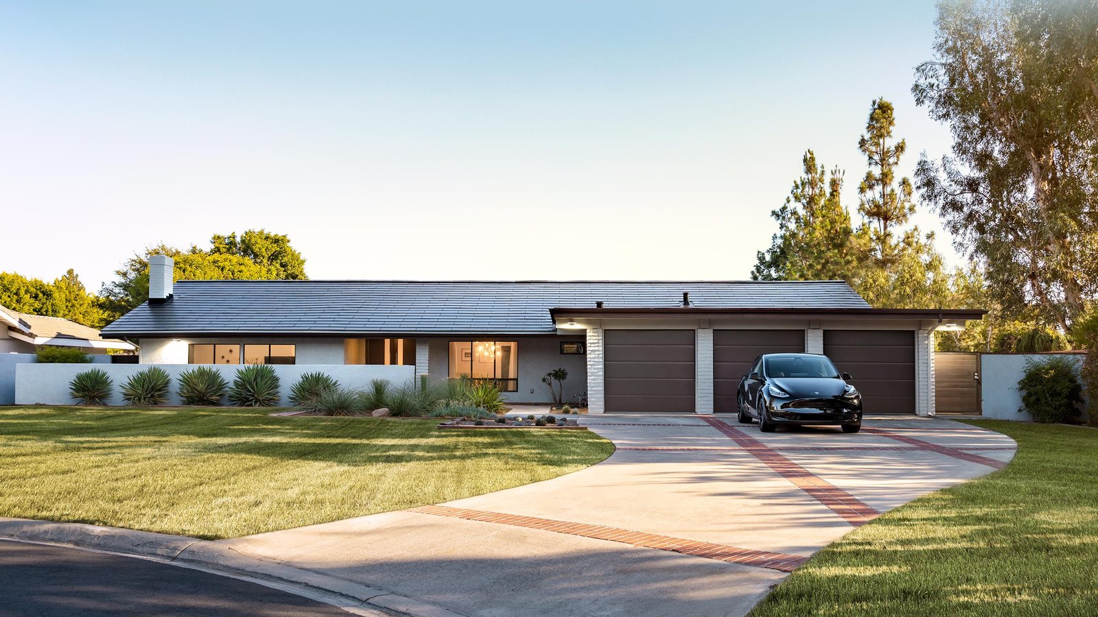 Single-story home with a full Tesla Solar Roof and a black Tesla parked in the driveway