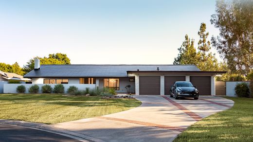 Single-story home with a full Tesla Solar Roof and a black Tesla parked in the driveway