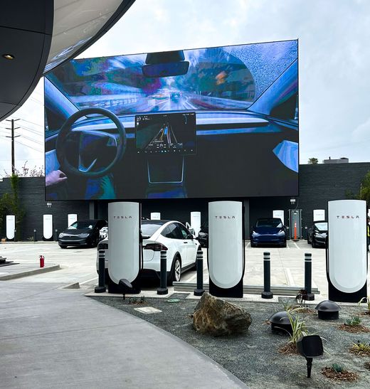 Hollywood Tesla Supercharger with a giant outdoor screen and vehicles at V4 stalls